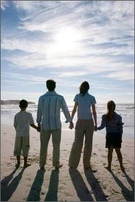 Picture Mom, Dad and two children holding hands on a beach.